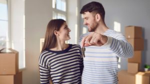A couple holding the keys to their new home among moving boxes