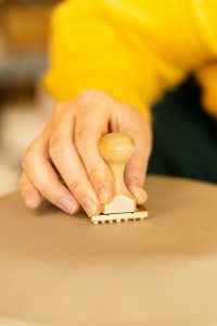 A hand pressing a wooden rubber stamp onto paper