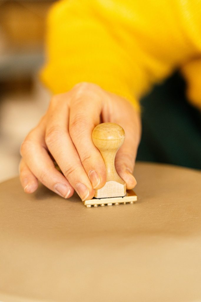A hand pressing a wooden rubber stamp onto paper