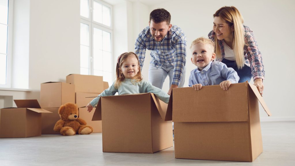 A family with two young children unpacking moving boxes in an empty living room