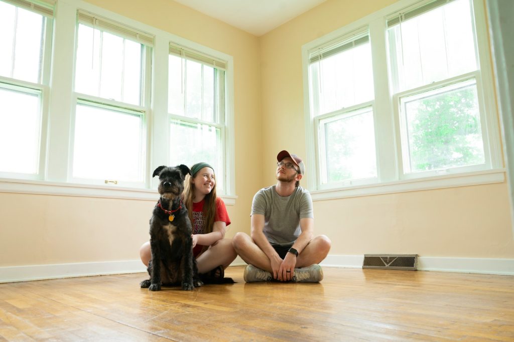A young couple and their dog sitting on the floor of an empty room