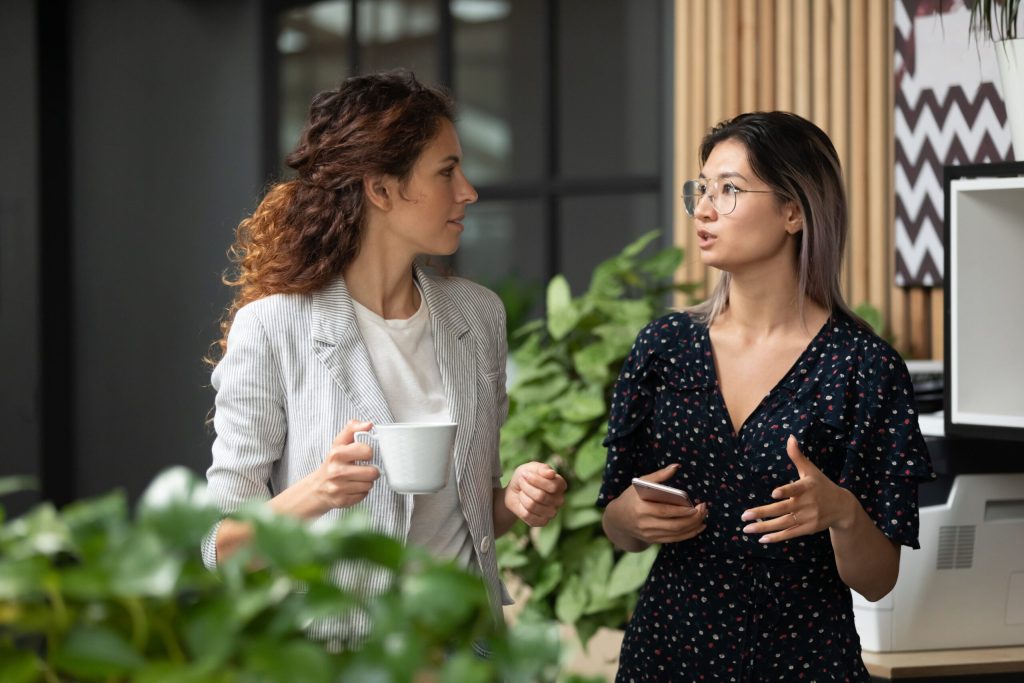 Two colleagues in conversation over coffee in a modern office
