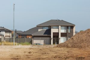 A vacant block ready to build on, with a completed two-storey home behind it