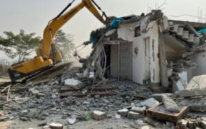 An excavator part-way through demolishing a single-storey house