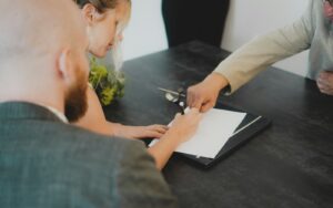 A couple signing loan paperwork across a desk