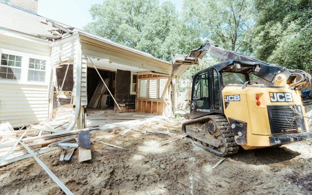 A bulldozer standing ready in front of a house due for demolition